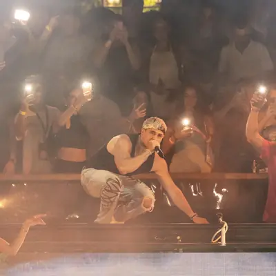 JK on the mic at a packed festival stage, the crowd filming with phone lights